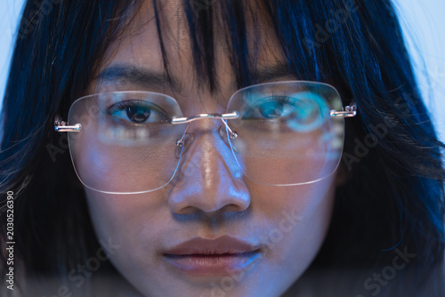 Detailed close up portrait of a beautiful young Asian female programmer wearing modern rimless eyeglasses with subtle code reflection on the clear transparent lenses