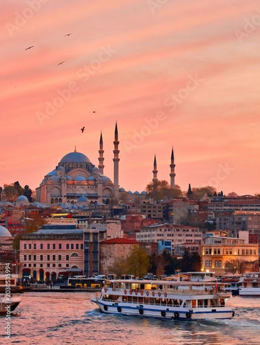 Beautiful sunset over Istanbul with Suleymaniye Mosque and ferry boat on the Golden Horn, Turkey