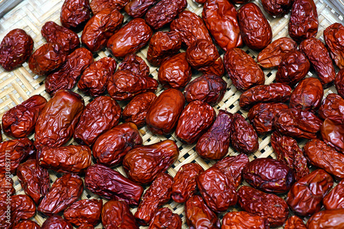 Close-up texture of dried red jujube fruits with wrinkled natural surfaces, commonly used in Asian cuisine, herbal drinks, and healthy food products. for food and ingredient background concept