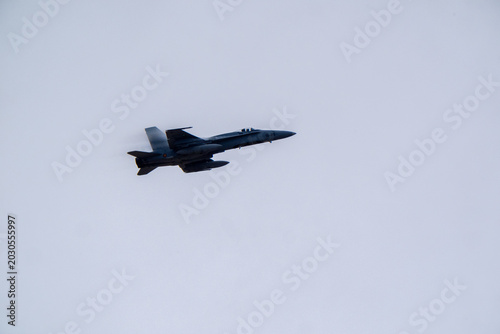 Quadro su tela Military jet aircraft in level flight against flat uniform gray overcast sky, sh