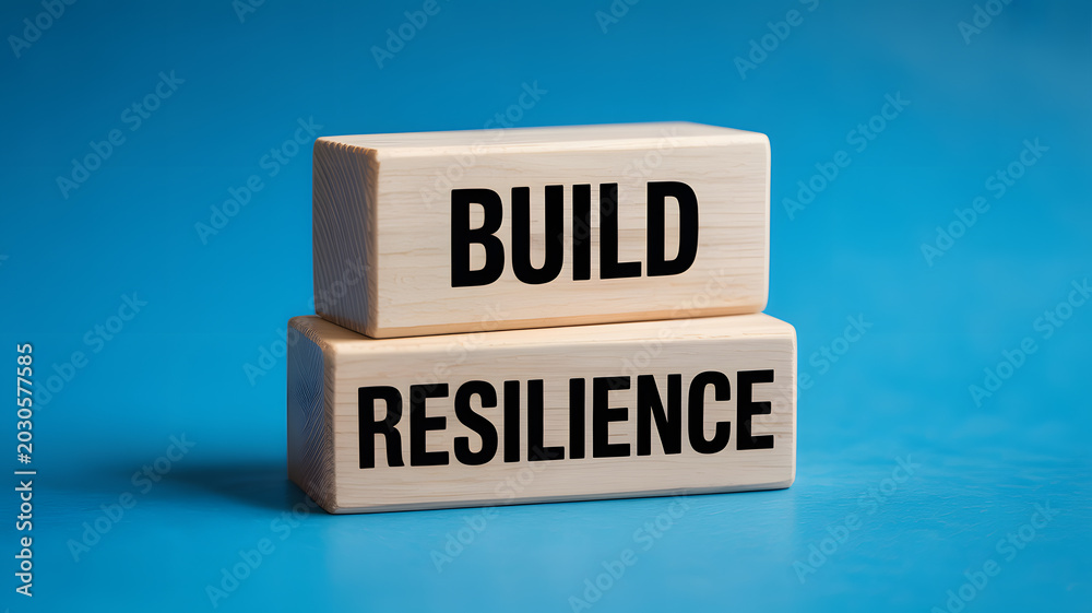 Two wooden blocks with build and resilience words on a blue background