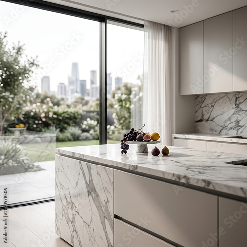 Modern Marble Kitchen Interior with Bowl of Grapes and Fresh Figs near Glass Doors Overlooking Garden and City Skyline