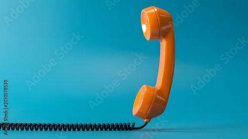 An orange telephone receiver stands alone on a blue background with a black cord