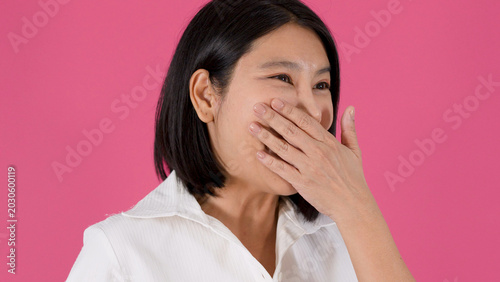 Tableau sur toile Cheerful Asian Woman Laughing and Covering Her Mouth Against Pink Background