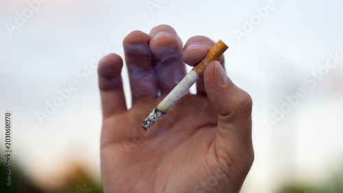 Obraz na plátně man holding burning cigarette outdoor close up view hand with smoke addiction un
