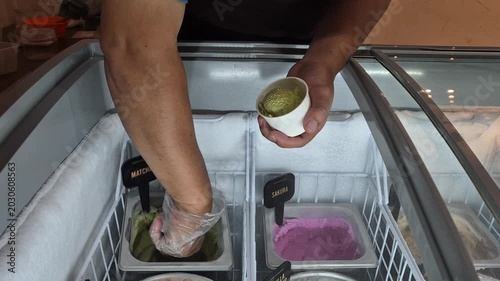 An ice cream vendor is scooping ice cream