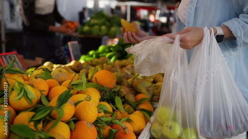 Woman selecting fresh fruit at outdoor farmers market, filling shopping bag with healthy produce for balanced diet, natural nutrition, and everyday wellness lifestyle.