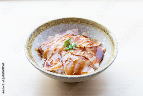 Obraz na płótnie Delicious Japanese Aburi Don featuring seared bacon topped with sweet teriyaki sauce and sesame seeds over rice in a ceramic bowl