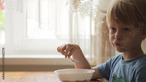 Little blond boy eating breakfast cereal
