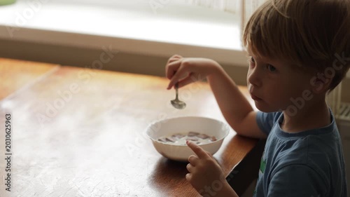 Cute little boy eating cereal for breakfast at home