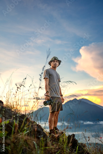 Indonesian man photographer standing on Mount Batur at sunrise in Kintamani Bali