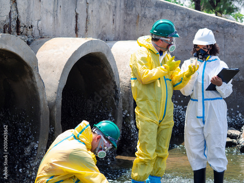 Fotografía Environmental engineers in chemical protective suits are collecting samples of contaminated water, ecologically and industrially, from nearby areas for testing