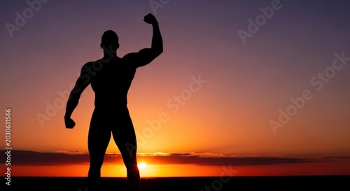 Silhouette of a muscular man raising arm against colorful sunset sky