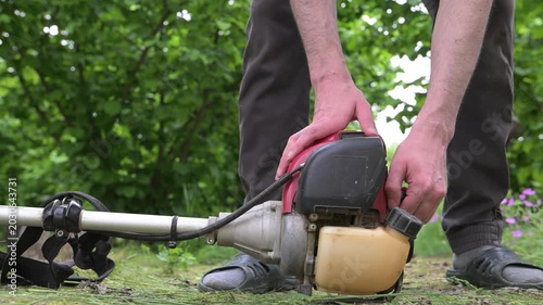 A farmer's hands start a gas-powered mower before work. Haymaking time in the countryside.
