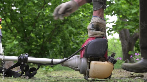 A farmer's hands start a gas-powered mower before work. Haymaking time in the countryside.