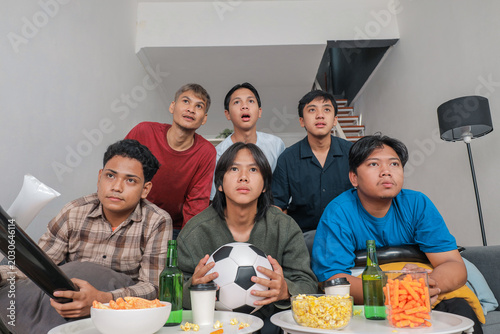 Cuadro en lienzo Group of Young Indonesian Men Watching Football Match Together at Home with Tens