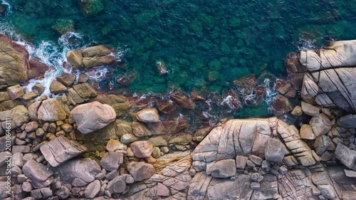 Aerial View of Rocky Coastline with Turquoise Waters crashing a Rugged Rocks Background	