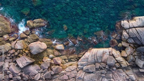 Aerial View of Rocky Coastline with Turquoise Waters crashing a Rugged Rocks Background	