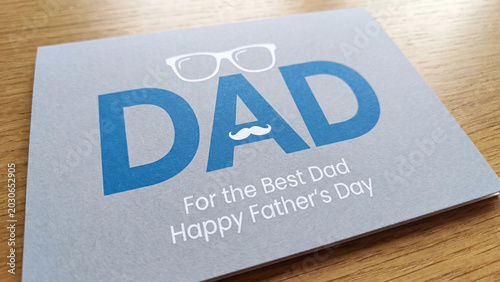 Father's Day blue greeting card with white mustache and glasses icons rests on a light wooden table surface to express gratitude and love for a parent on their special annual holiday.