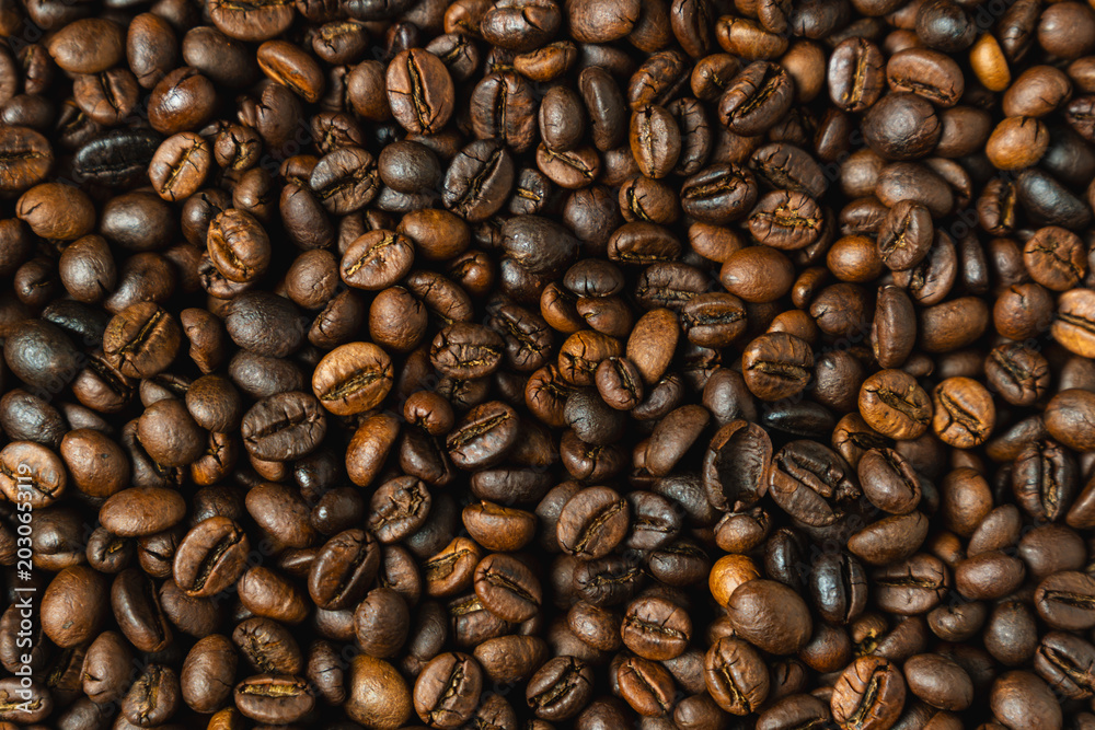 Fototapeta premium Close-up view of roasted coffee beans with rich brown tones and detailed texture, top down