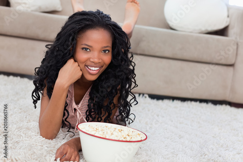 Foto African American woman lounging on white shag rug at home, wearing pink top, hol