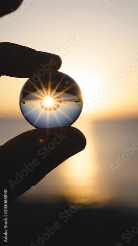 Hand Holds Crystal Ball with Sun Flare Reflection