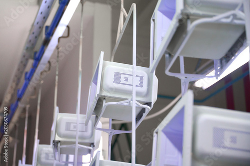 Microwave oven casings moving along overhead conveyor in powder coating workshop