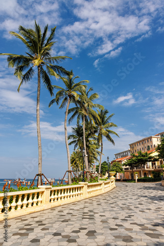 Phu Quoc, Vietnam - January 3 2026: Palm-lined tropical promenade near seaside restaurant in Phu Quoc