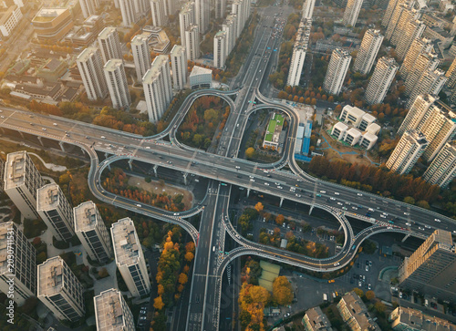 Modern highway system with active traffic flow on multiple lanes, surrounded by urban residential budlings rich autumn colors in China
