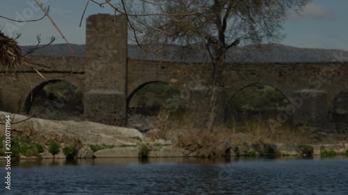 Old stone bridge with multiple arches crossing a tranquil river