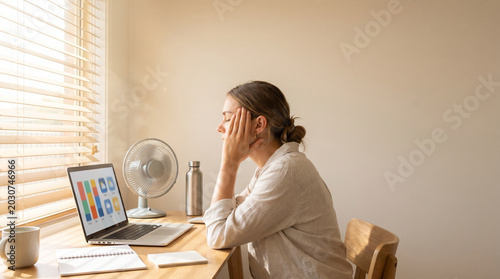 Remote worker under heatwave stress in a home office