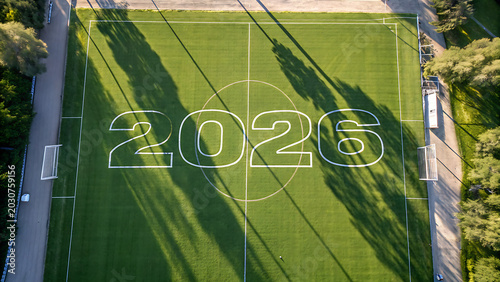 Aerial Top-Down View of a Green Soccer Field with 2026 Text and Tree Shadows