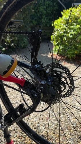 Cleaning bicycle rear cassette with brush and water in outdoor setting