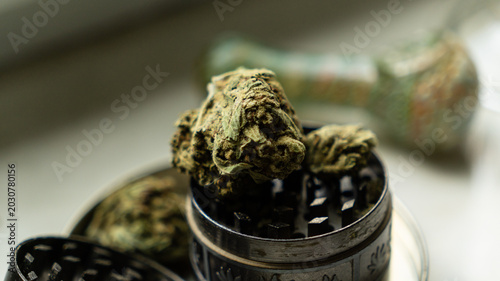 Fotografia Top down view of a large dry cannabis bud, matches, and an open metal grinder inside a metal stash tin