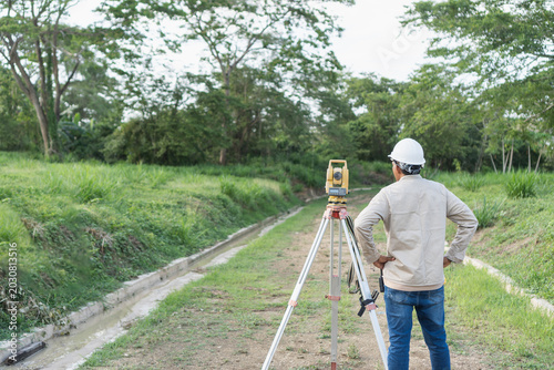 Surveyor using total station for topographic land measurement