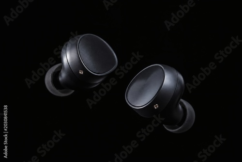 Wireless black earbuds floating on dark background
