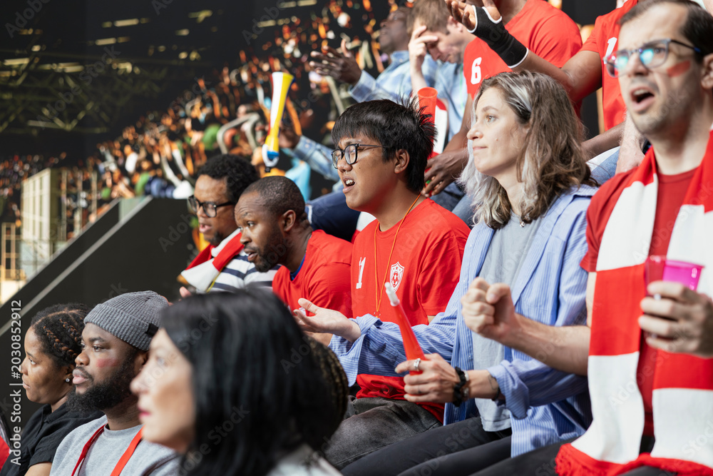 Obraz premium Diverse football supporters watching a tense last minute play during soccer match in stadium stands with passionate crowd reactions. Passionate fans react to close call with anticipation.