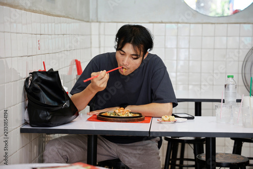 Foto Young Asian Man Eating Noodles Alone in Casual Local Restaurant