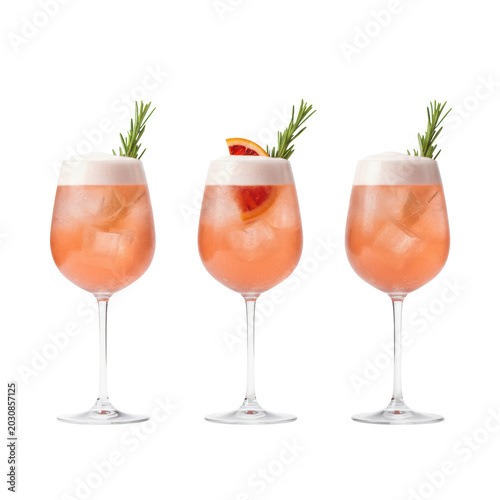Three elegant wine glasses with effervescent coral pink spritz, ice, foam, rosemary, and condensation, one with a red citrus wedge, on a transparent background. Luxurious refreshment