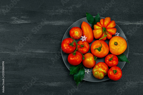 Fotografija Assorted red and orange homegrown heirloom tomatoes with green leaves and small