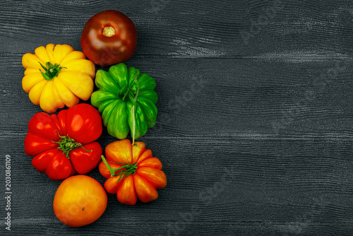 Photos Multicolored homegrown heirloom beefsteak tomatoes on a dark wooden background
