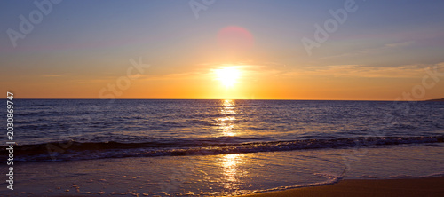 Golden sunset over the ocean with waves and colorful sky.