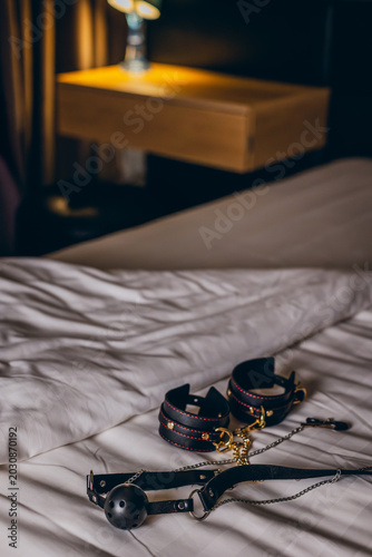 Foto Bondage restraints arranged on rumpled bed near nightstand