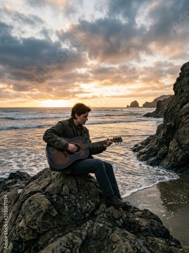 Person playing guitar on beach rock, sunset ocean view.