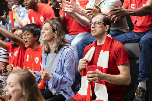 Foto Red team football supporters showing mixed reactions in crowded stadium stands during tense live soccer match