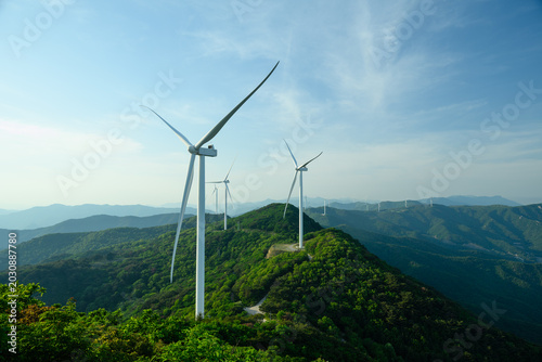 Foto Wind Turbine Farm on a Forested Mountain Ridge at Golden Hour