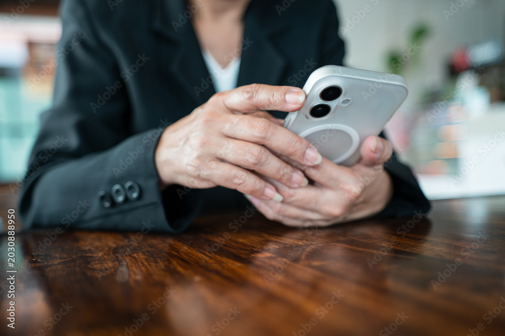 Fototapeta premium Close-up of businesswoman hands using and holding a smartphone at workplace.