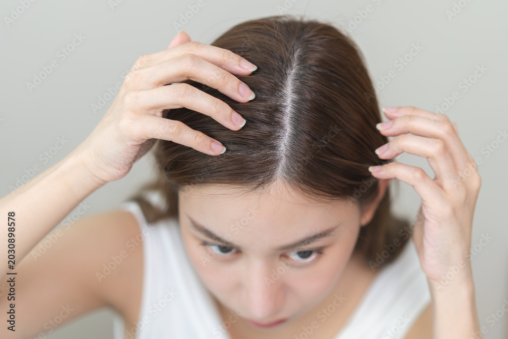 Naklejka premium Damaged hair symptom, problem hair fall asian young woman, girl worry about balding, looking at scalp in mirror, hand in break into front hair loss, thin problem. Health care treatment for beauty.