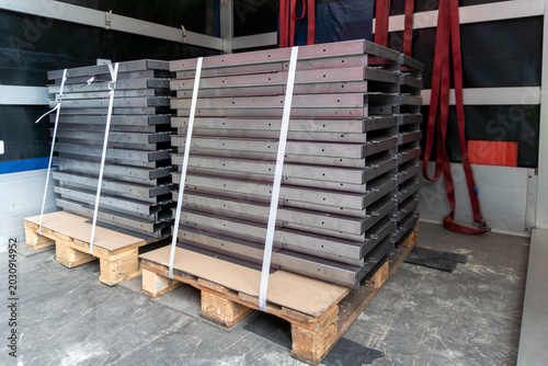 Stacked rectangular metal frames strapped on wooden pallets inside a cargo truck, showing industrial transport, warehouse logistics, steel components, freight loading, and construction supply delivery