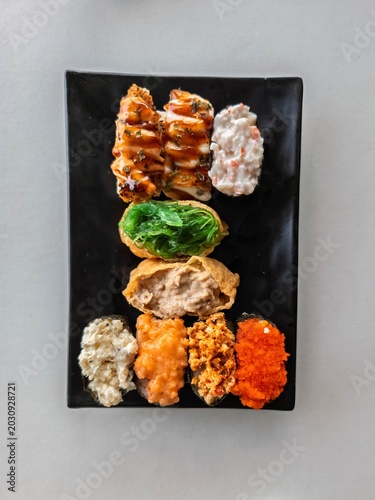 Top view of sushi set in a black plate.